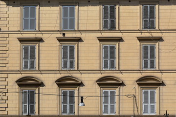 Exterior yellow wall of old building with windows and shutters