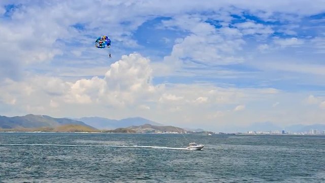 parasailing over azure sea boat makes tight turn against hills