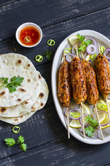 chicken kebab, salad with tomatoes, onions and olives, homemade tortilla is a healthy and delicious meal, on a dark wooden background