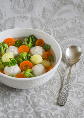 soup with chicken meat balls, potatoes, broccoli and carrots in a white bowl, a Healthy and tasty lunch