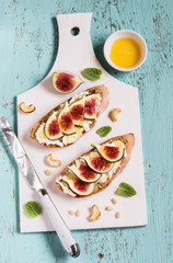 sandwich with soft cheese, figs and honey - delicious appetizer with wine, healthy Breakfast or snack on a light wooden surface