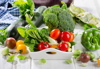 Fresh green organic vegetables on a white wooden background.