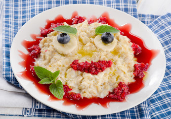 Smiling oatmeal and fresh berries for a healthy breakfast.