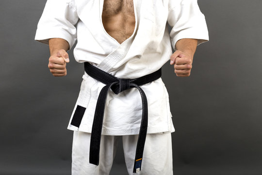 Young man in white kimono and black belt training martial art