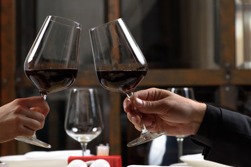Couple drinking red wine in restaurant. Close-up hands with