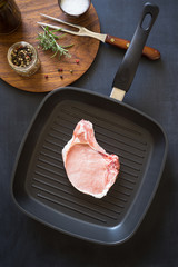 Raw pork rib chops on the grill frying pan with spices and herbs
