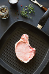Raw pork rib chops on the grill frying pan with spices and herbs
