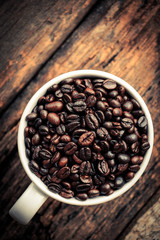 Coffee bean in cup put on old wooden table.