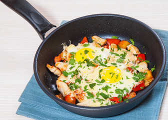 fried eggs with chicken breast, pepper and cheese in a frying pan