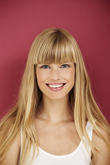 Naklejka premium Happy and smiling young woman on red background