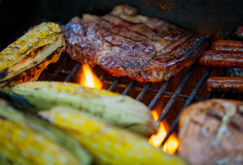hot dogs, steaks and salmon on a grill