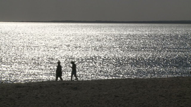 People walking along the beach at dusk