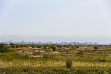 The outlines of the city on the horizon . 
City silhouette on a rural landscape .