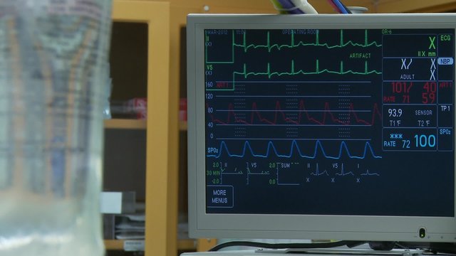 IV drip bag with vitals monitor in background during spinal surgery