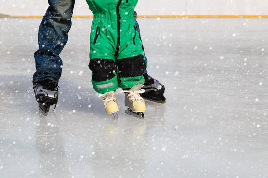 father and child learning to skate in winter