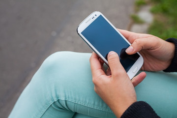 Mobile phone in a woman's hand on park background, message, sms.
