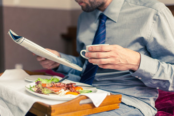 Businessman reading newspaper during breakfast at home/hotel. In
