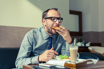 Businessman eating breakfast at home/hotel. Indoor photo.