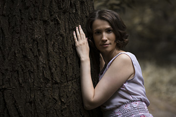 Young woman resting on tree by body and hand