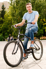 Obraz premium Young man sitting on the bike in the park