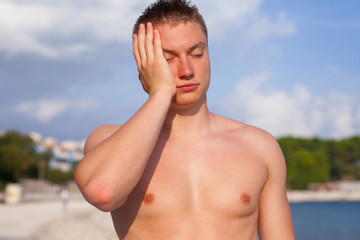 Fototapeta na wymiar Man standing on the beach and hurting because of headache.