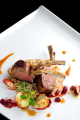 Fine dining roasted Lamb Chops on whole grain rice, mini aubergines and a sauce garnished with beerot, tomato and basil