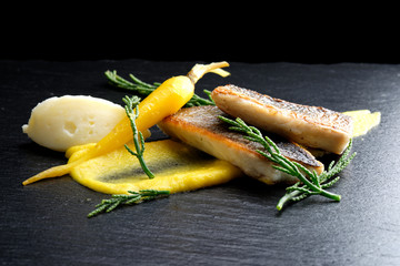 Fine dining Seabass fillets on carrot potato purree and spices