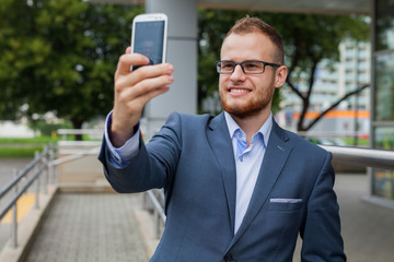 Caucasian businessman outside office using mobile phone on an office terrace.