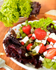 Green salad with strawberries, cottage cheese and olive oil