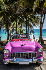 Pinker Oldtimer parkt am Strand in Kuba