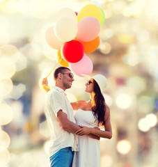 smiling couple with air balloons outdoors