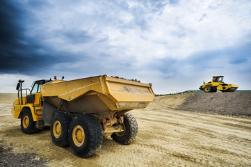 Muldenkipper und Radwalze auf Baustelle