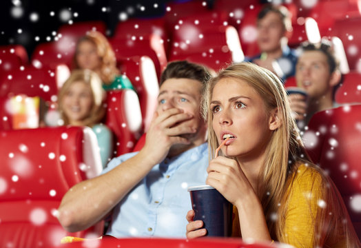 friends or couple watching horror movie in theater