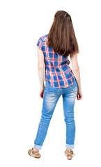 Obraz premium back view of standing young beautiful woman in jeans.