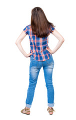 back view of standing young beautiful  woman.  girl  watching. Rear view people collection. A young girl in a checkered blue shirt is resting in the palm of her waist.