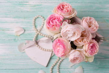 Pink roses in wooden pot, decorative heart and pearls