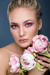 Nice young woman holding peonies near her chest