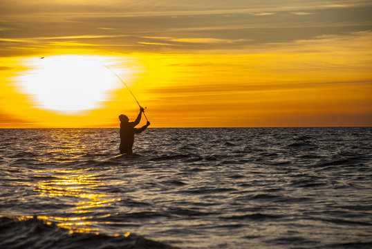 Angler fishing at the coast in an Autumn sunset