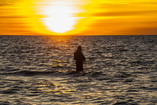 Angler fishing at the coast in an Autumn sunset