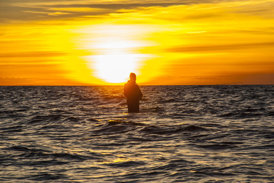 Angler fishing at the coast in an Autumn sunset