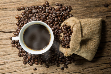 White coffee cup and coffee beans on wood background.