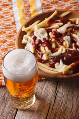 Canadian food: beer and fries with sauce close-up. Vertical
