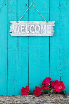 Welcome sign hanging hanging on fence by rose covered log