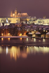 Night romantic colorful snowy Prague gothic Castle with Charles Bridge, Czech Republic
