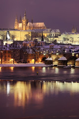 Night romantic colorful snowy Prague gothic Castle with Charles Bridge, Czech Republic