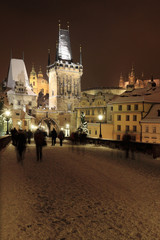 Fototapeta na wymiar Night colorful snowy Prague gothic Castle with Bridge Tower and St. Nicholas' Cathedral and Sculptures from the Charles Bridge, Czech republic