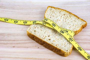 Bread wrapped with measuring tape on wooden surface. Healthy diet concept. Selective focus.