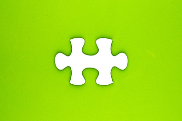 Piece of jigsaw puzzle on rough green surface.