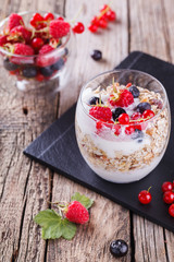 Breakfast with muesli, yogurt,honey and fresh berries in a glass on a wooden background. selective focus