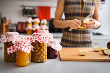 Preserved fruit in glass jars with woman quartering apple